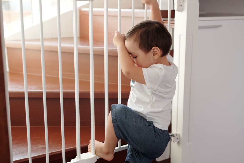 Toddler beside a safety gate at the top of the stairs in a rental
