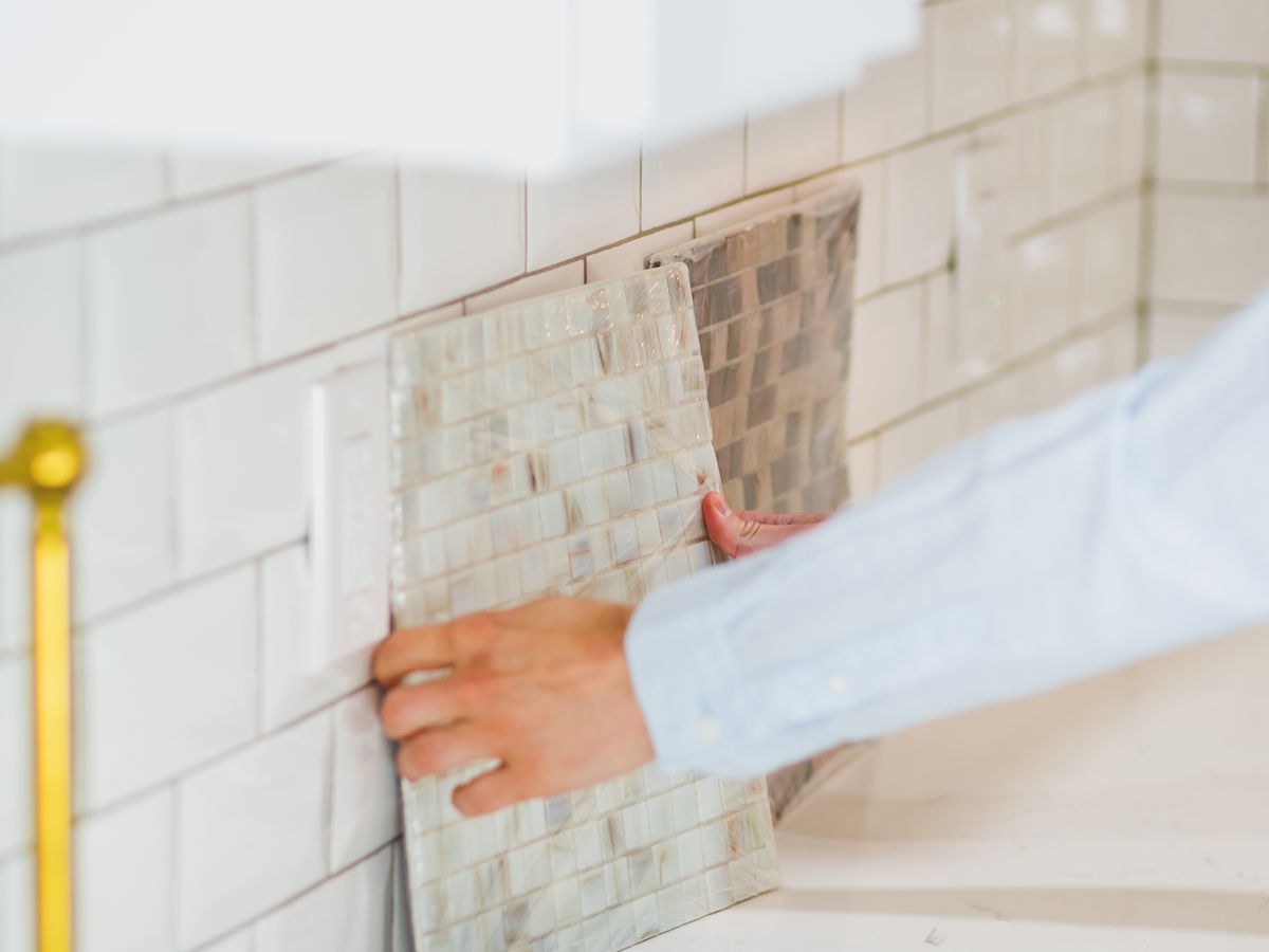 A person choosing a tile design on a wall for a rental kitchen backsplash makeover