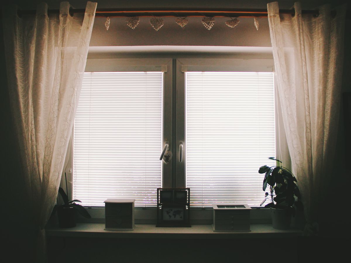 Window framed with curtains and blinds to hide an AC unit