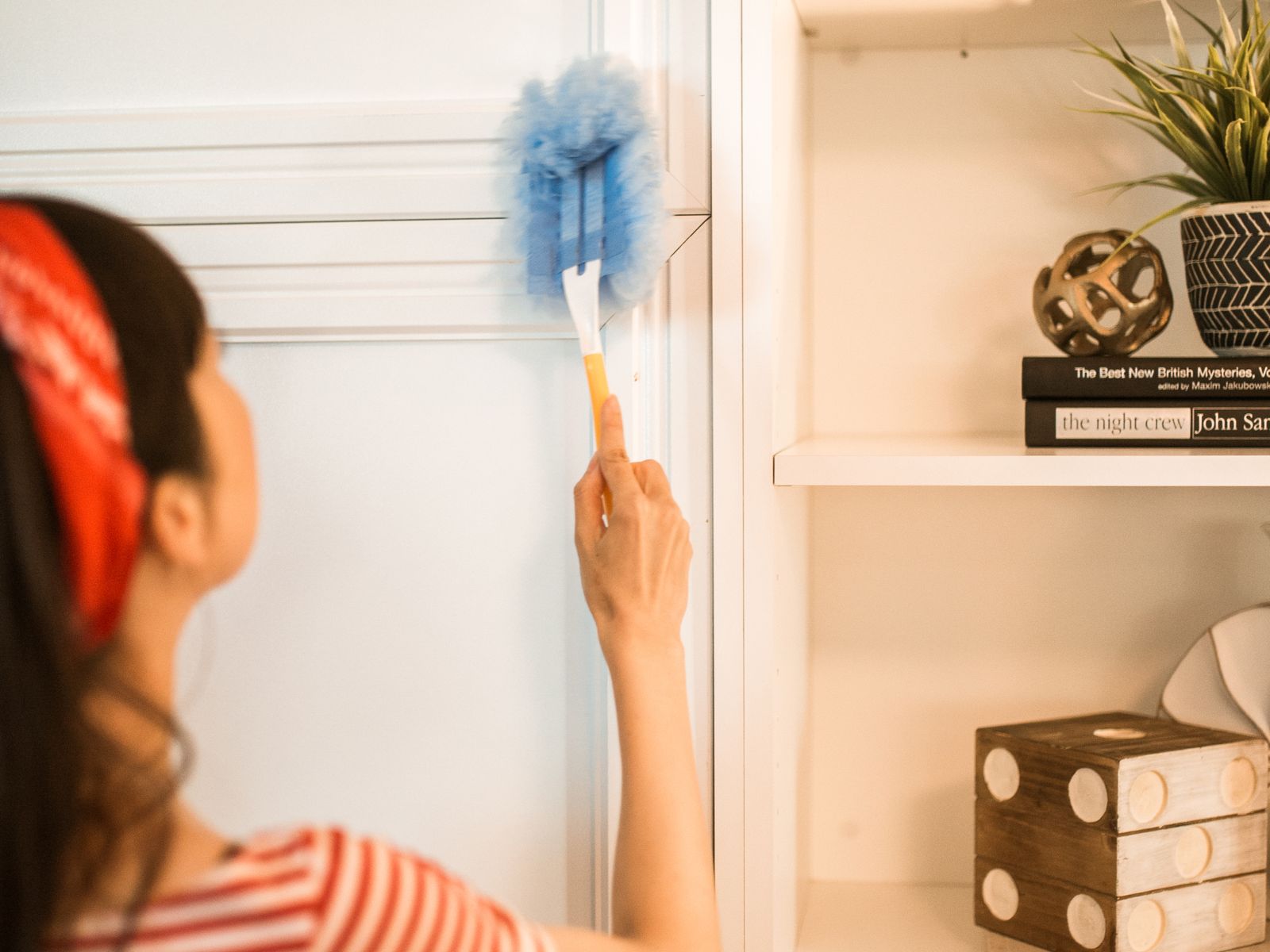 Dusting shelves while preparing a rental for a move-out inspection