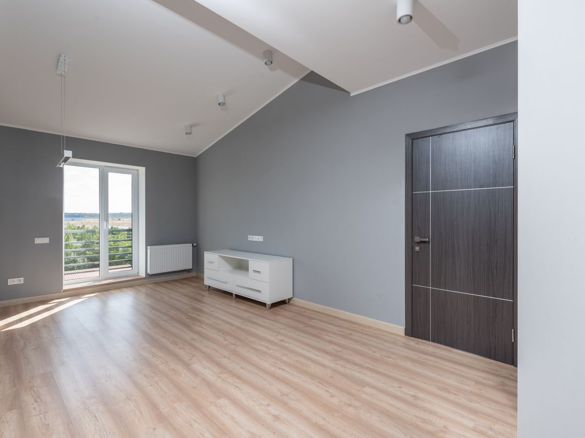 Empty rental apartment room with wood floor and bare walls being assessed for wear and tear