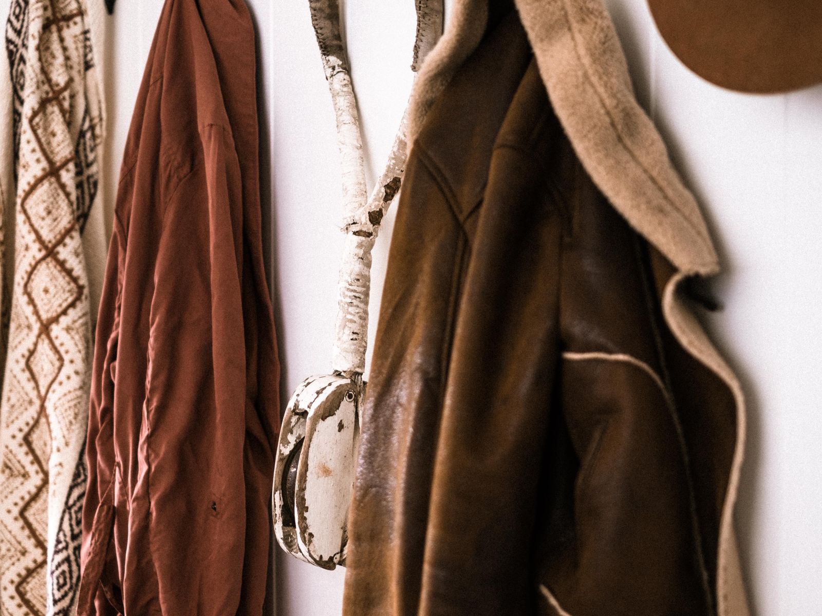 Wall hooks holding a coat and hat as entryway organization