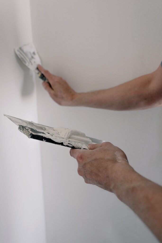 Renter using a putty knife to fill nail holes and repair small wall damage before moving out