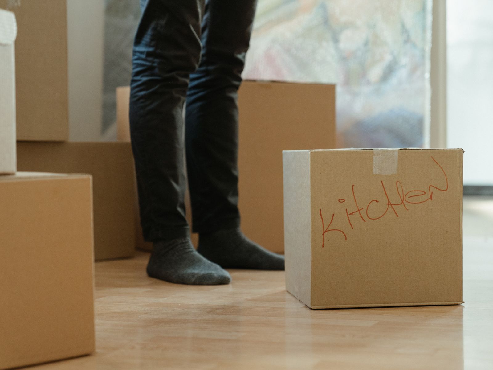 Person standing among labeled moving boxes while unpacking a new rental