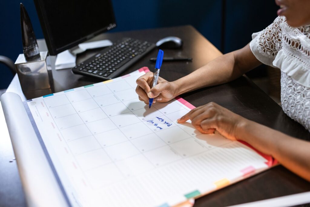 Person writing move-out timeline reminders in a desk calendar before handing over keys