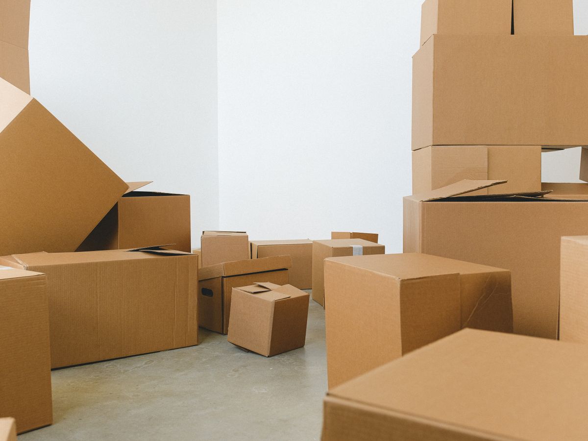 Stacked cardboard moving boxes in a bright empty rental room during the first 48 hours