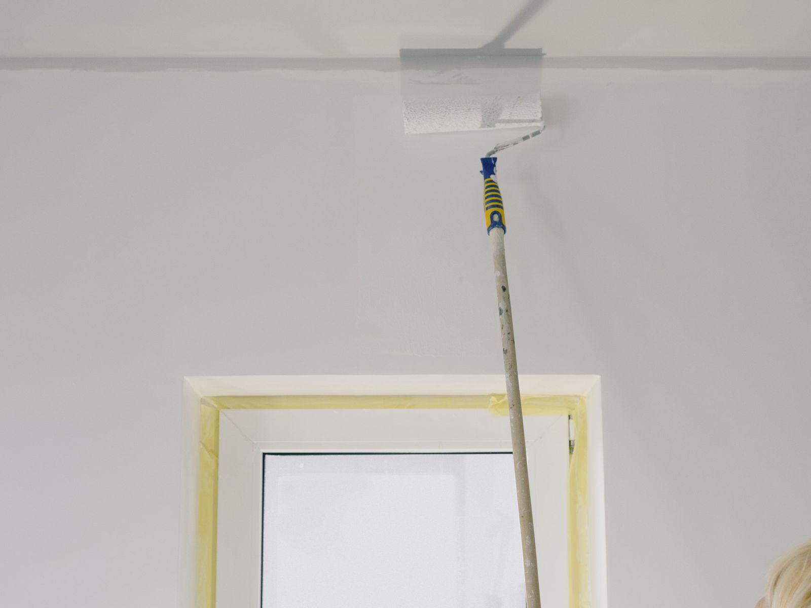 Touching up a repaired wall with a paint roller to match the original color
