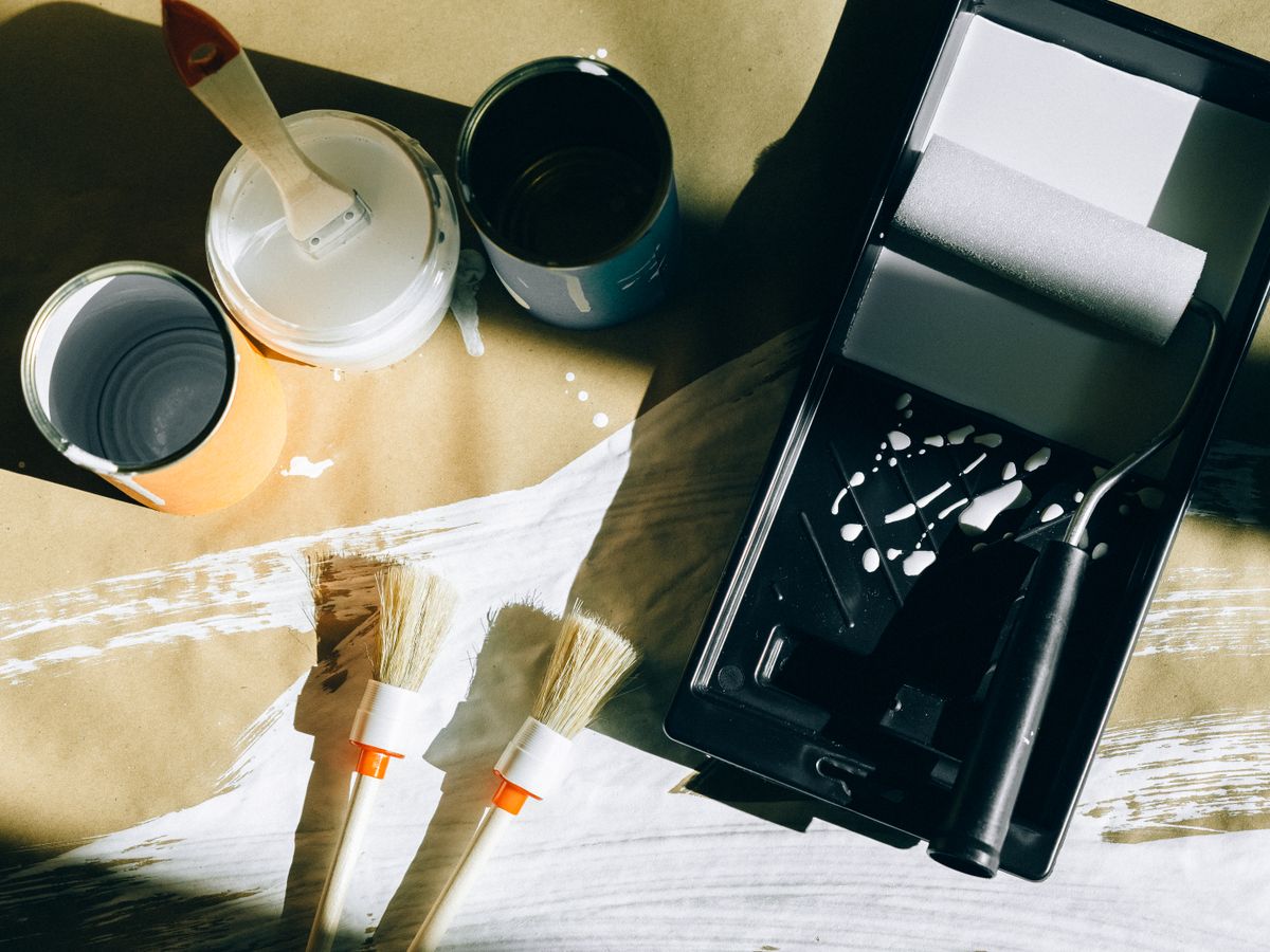 Paint cans, brushes and a roller tray laid out for budget-friendly wall touch-ups before move-out