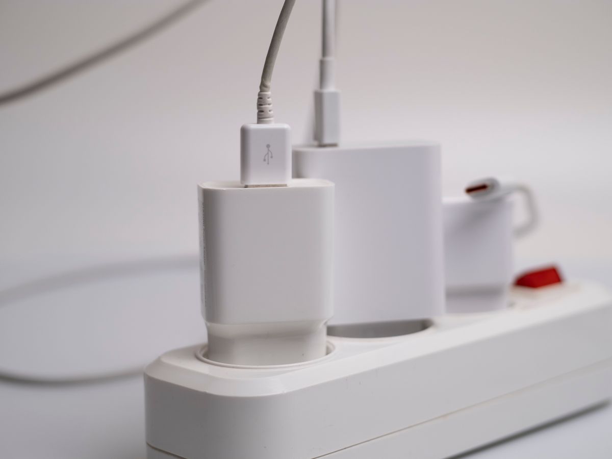 White power strip with chargers plugged in, used for tidy no-drill cable management behind a TV