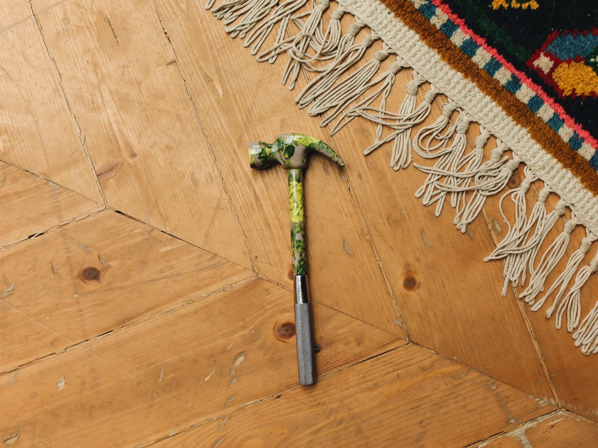 A hammer and repair tools on a wooden floor ready for small rental fixes