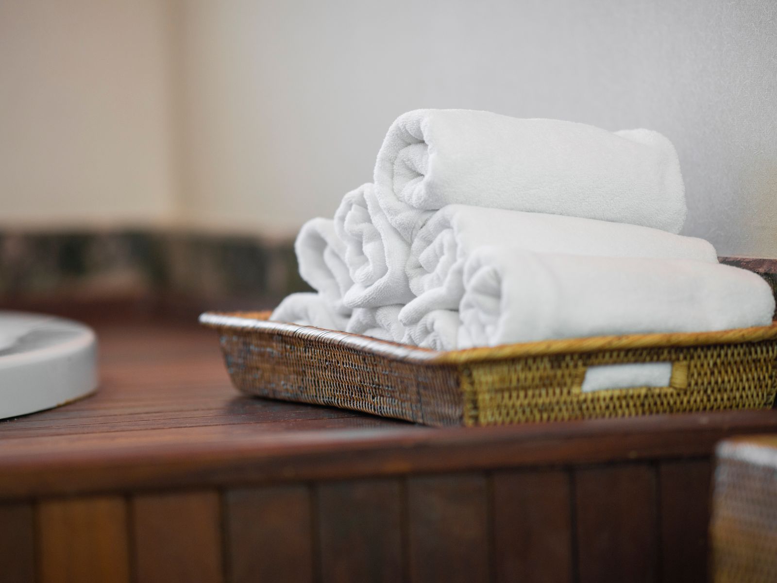 Rolled white towels in a woven basket adding a spa look to a rental bathroom