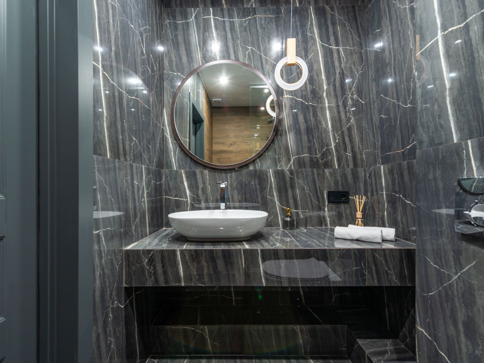 Round framed mirror above a marble vanity improving rental bathroom lighting