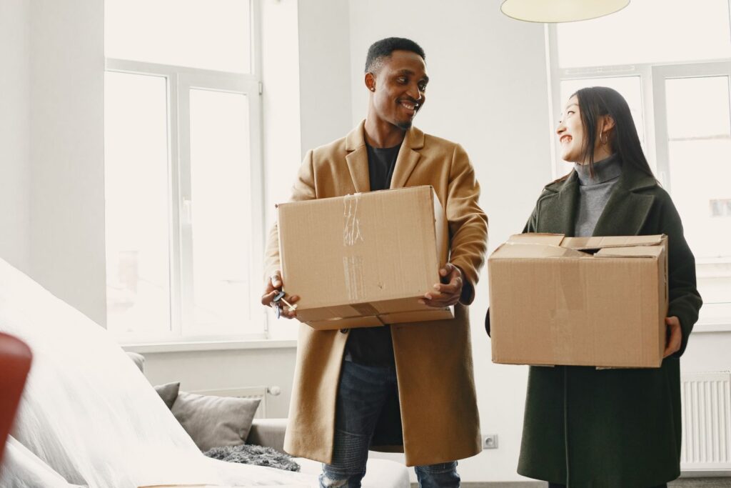 A couple carrying boxes into a small rental they will share
