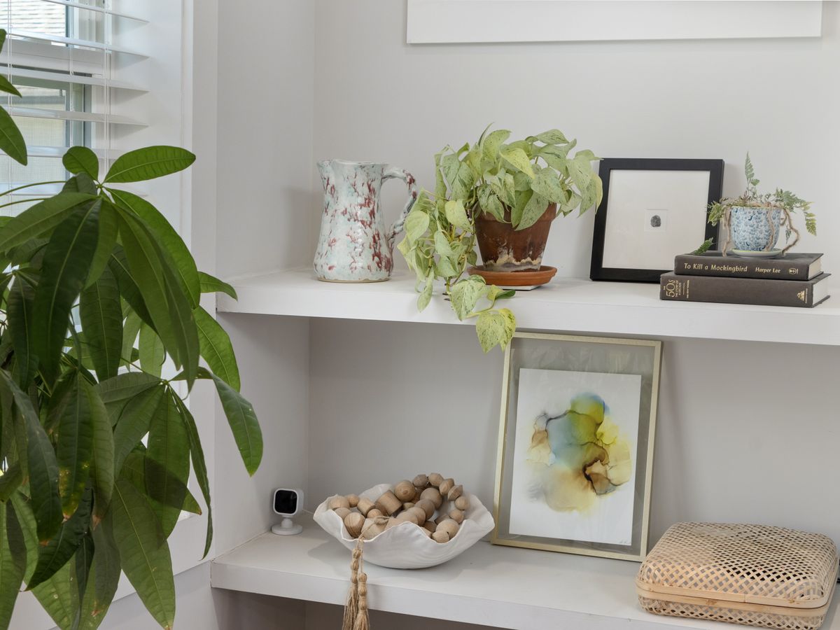 Shelf styled with plants, art, and books adding personality