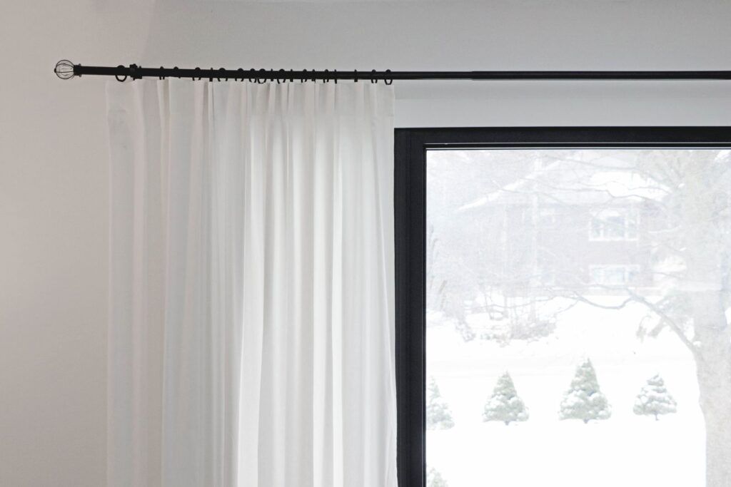 Tension rod holding curtains across an apartment window
