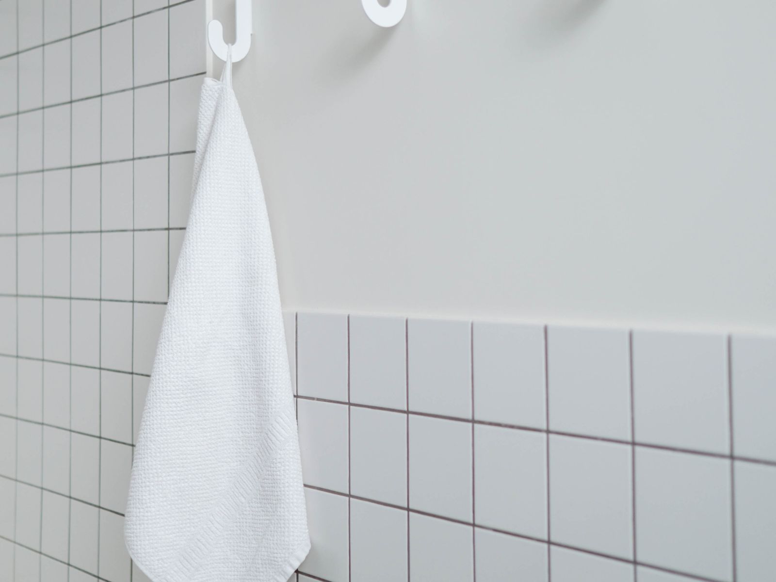 White towel hanging from an adhesive wall hook in a bathroom